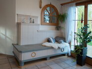 Gemütlicher, weisser Kachelofen mit Sitzbank